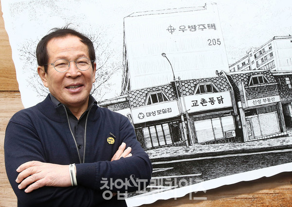 교촌에프앤비㈜ 창업주 권원강 전(前) 회장이 교촌치킨 1호점 일러스트 앞에서 사진 촬영을 하고 있다.